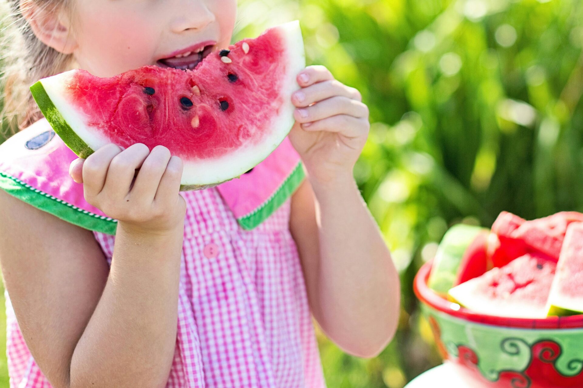 girl-eating-sliced-watermelon-fruit-beside-table