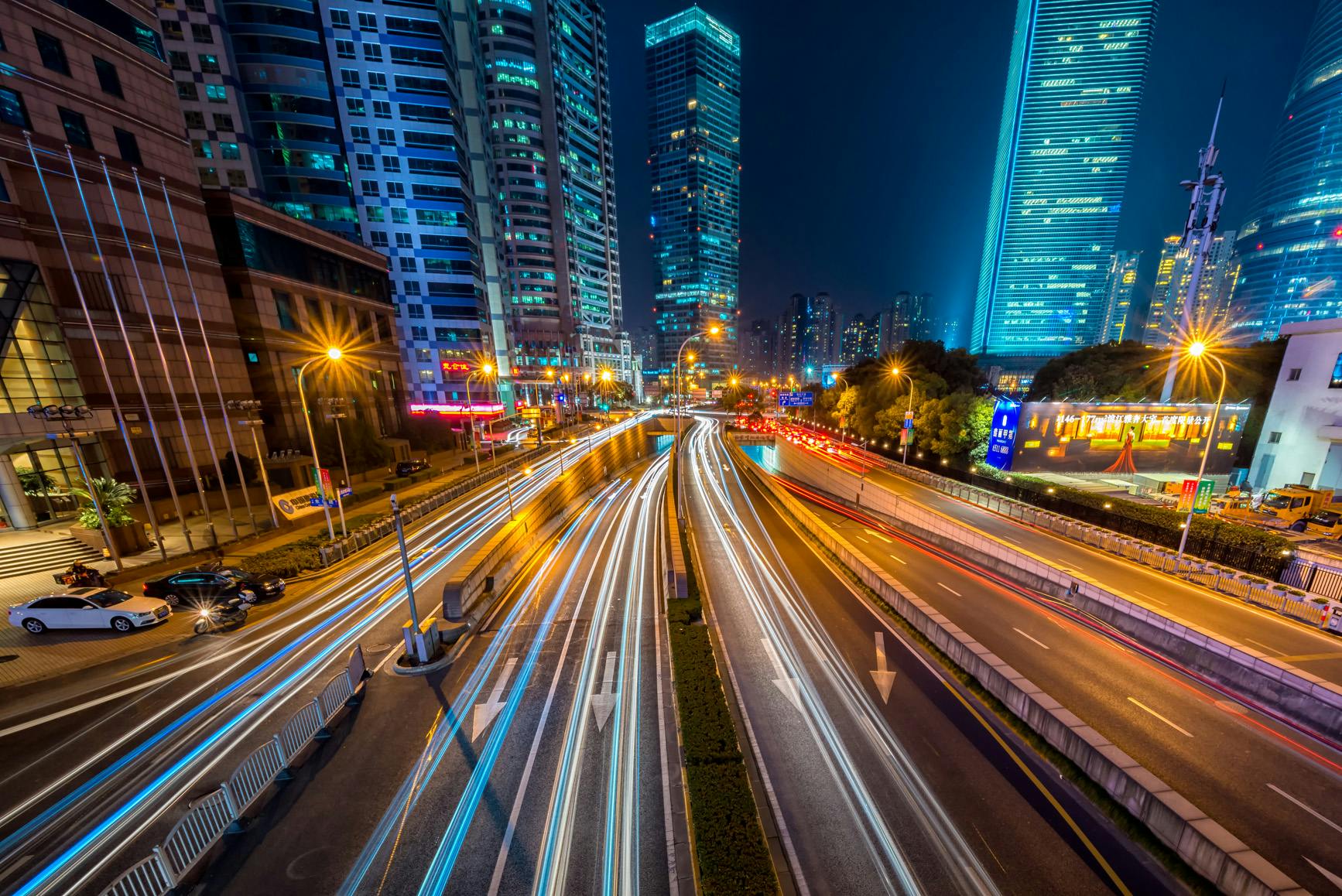 timelapse-photography-of-vehicle-on-concrete-road-near-in-high-rise-building-during-nighttime