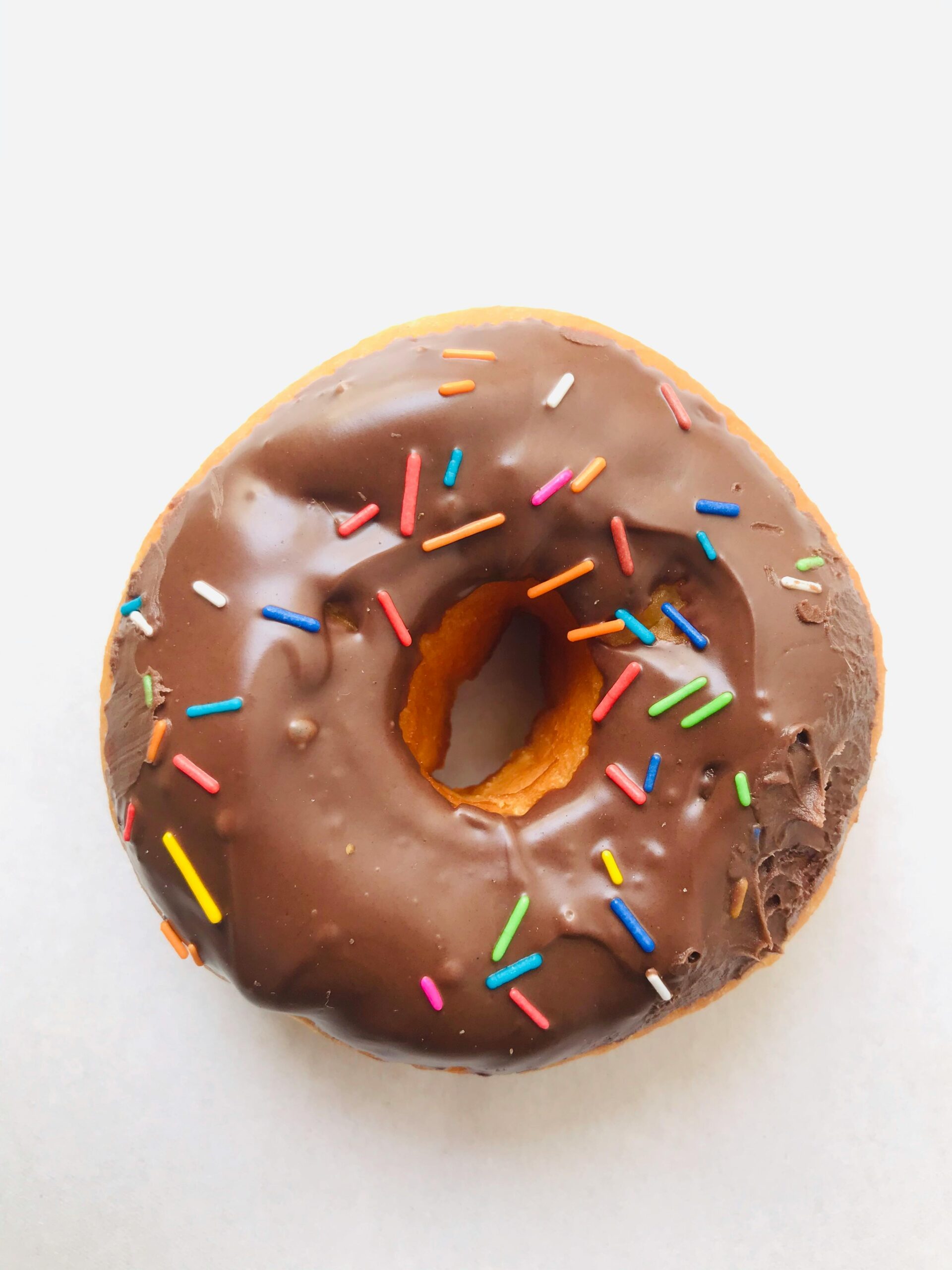 chocolate-coated-doughnut-with-sprinkles-on-a-white-surface