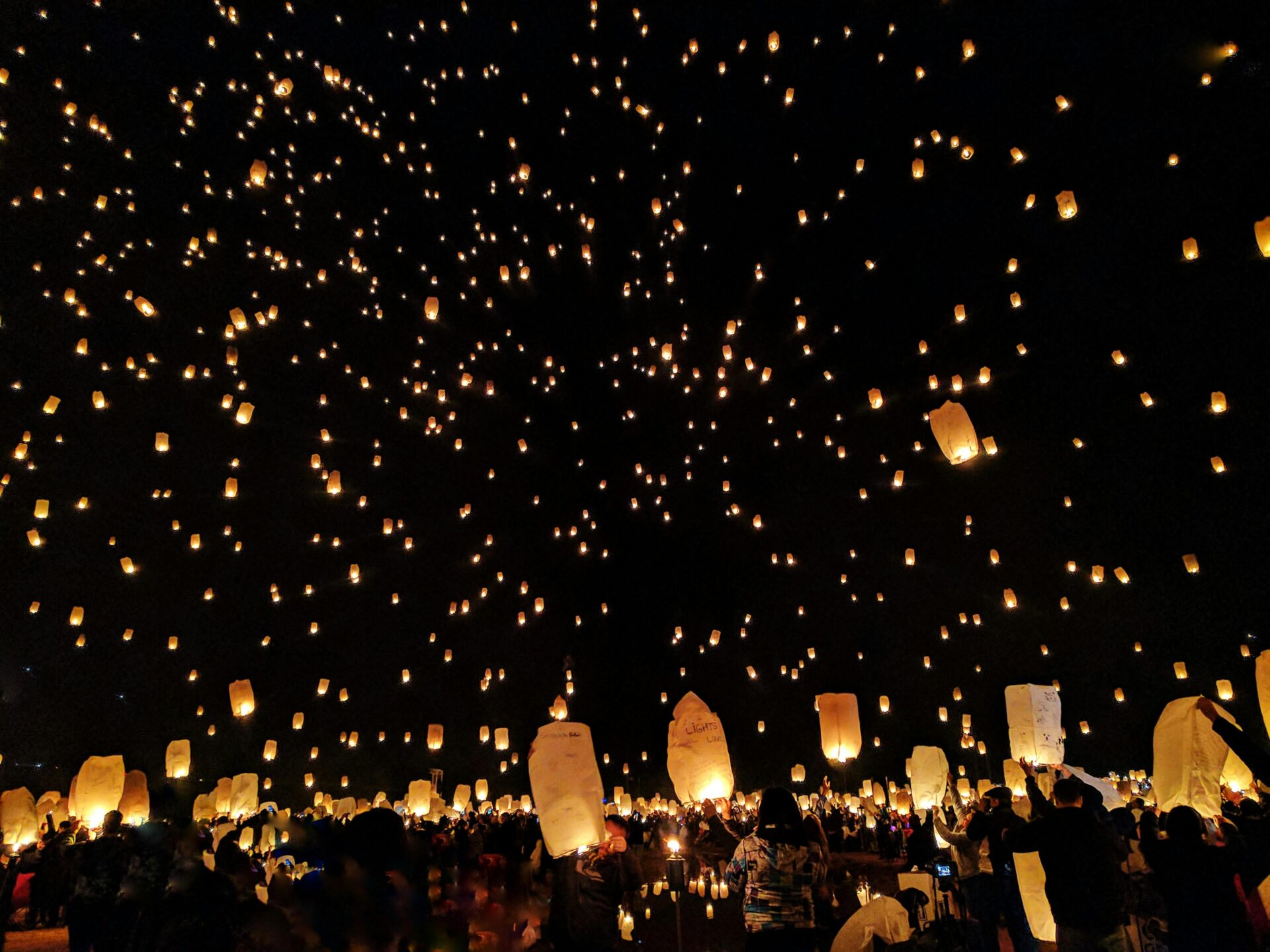 group-of-people-throwing-paper-lantern-on-sky-during-night