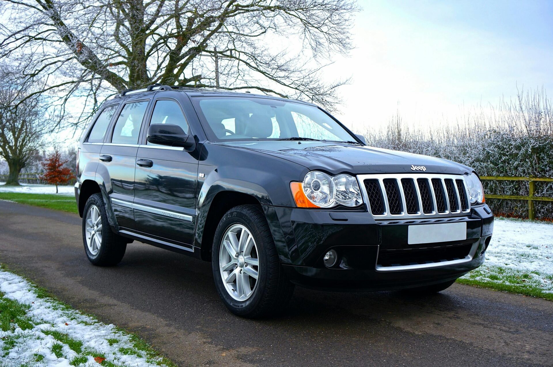 black-jeep-suv-on-black-asphalt-road-near-on-snowy-grass-lawn