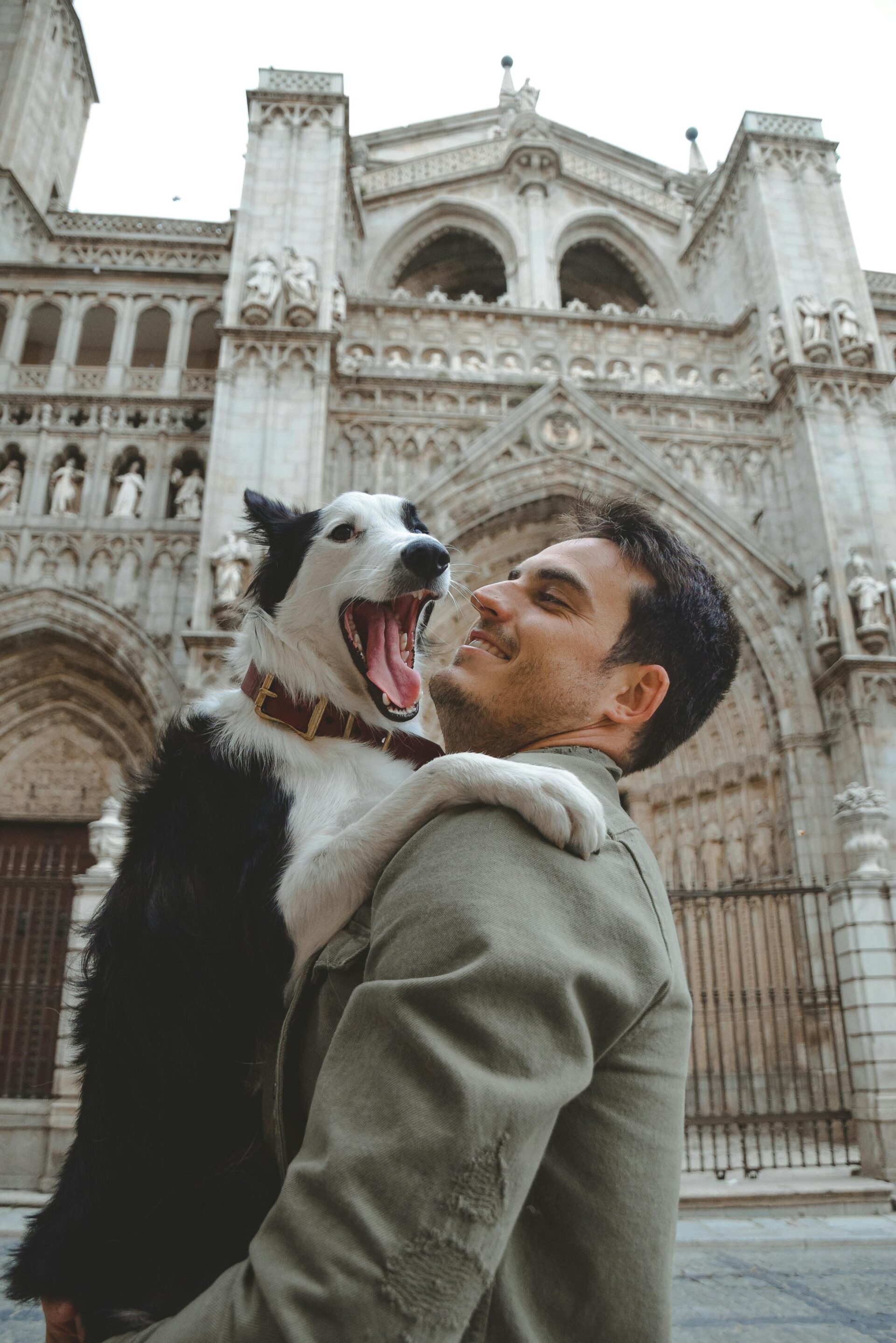 a-man-holding-a-dog-in-front-of-a-cathedral