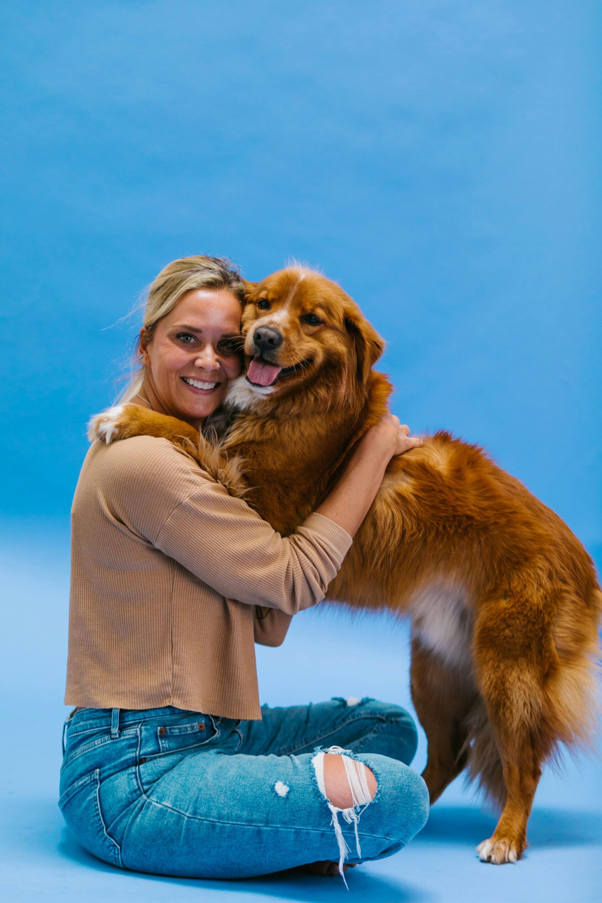 woman-wearing-a-sweater-sitting-and-hugging-a-dog